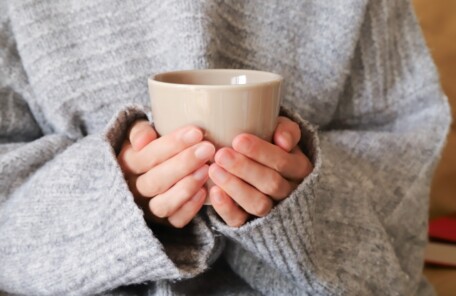 冬の朝、マグカップを両手で包んで手を温める様子