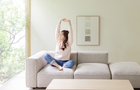 ソファで軽くストレッチしながら体を整える女性のイメージ