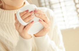 あたたかい飲み物を手に持ちながらひと息つく女性のイメージ
