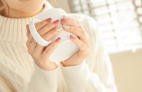 あたたかい飲み物を手に持ちながらひと息つく女性のイメージ