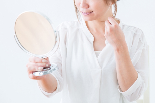 鏡を見ながら髪を気にする女性のイメージ