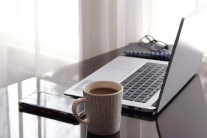 ノートパソコンとマグカップが置かれた、落ち着いて作業しやすい机