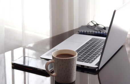 ノートパソコンとマグカップが置かれた、落ち着いて作業しやすい机