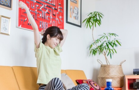 ソファで伸びをする女性。セルフケアはゆるゆると。続かなくても大丈夫です。