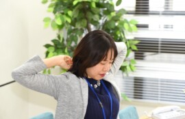首や肩の緊張を感じながら少し疲れた様子を見せる女性のイメージ