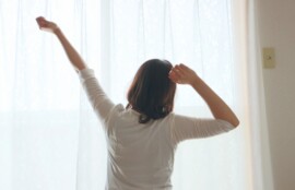 自宅で朝の光の中、無理のない伸びをして体を整えるイメージ