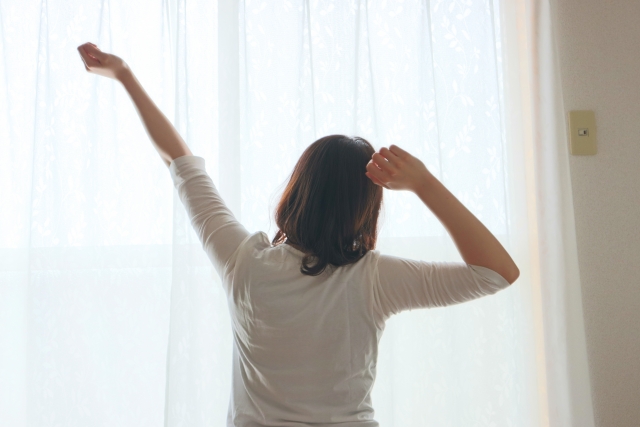 自宅で朝の光の中、無理のない伸びをして体を整えるイメージ